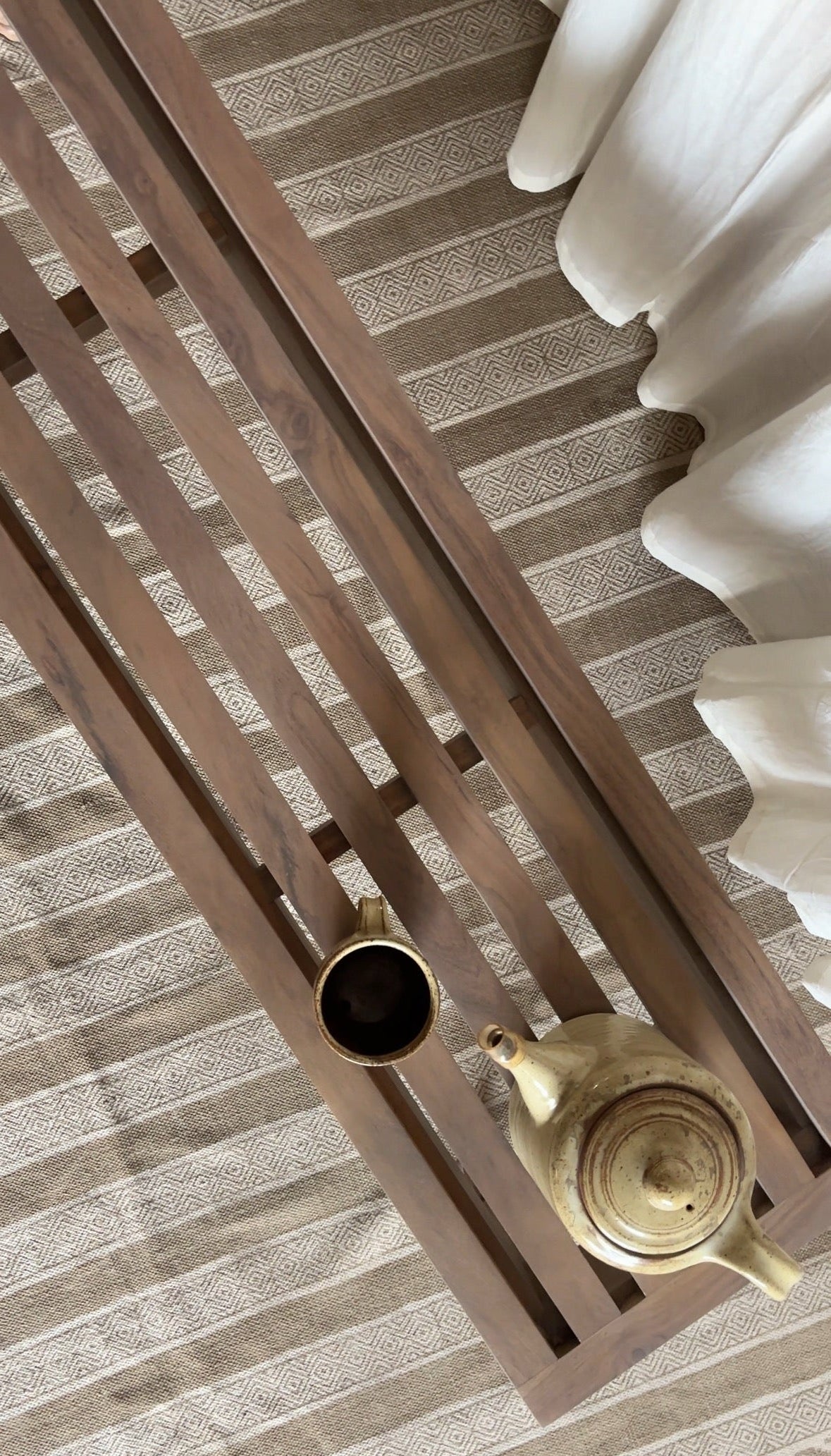 Tea cup and teapot on a wooden bench with a striped background