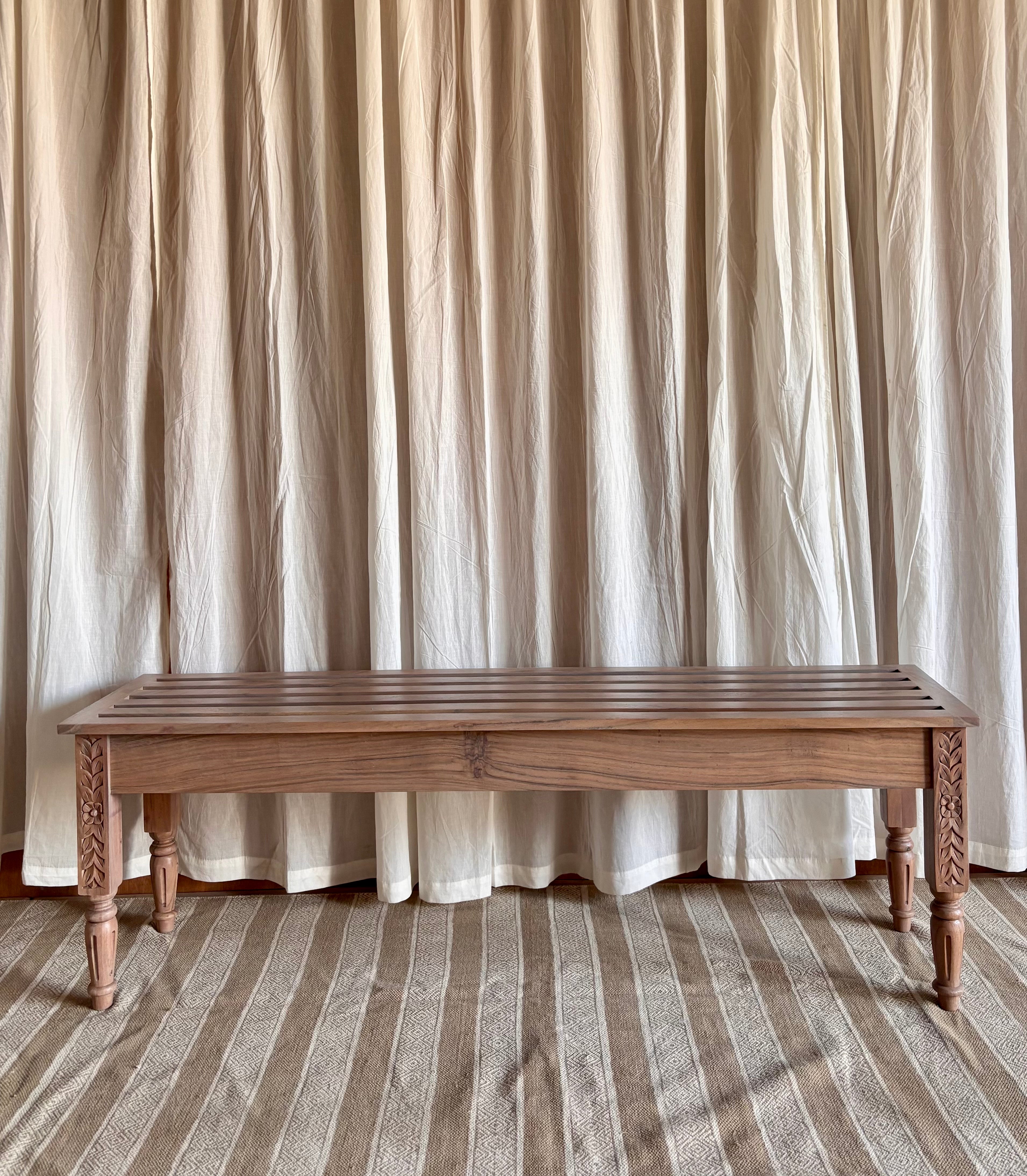 Wooden bench in front of a curtain with a striped floor